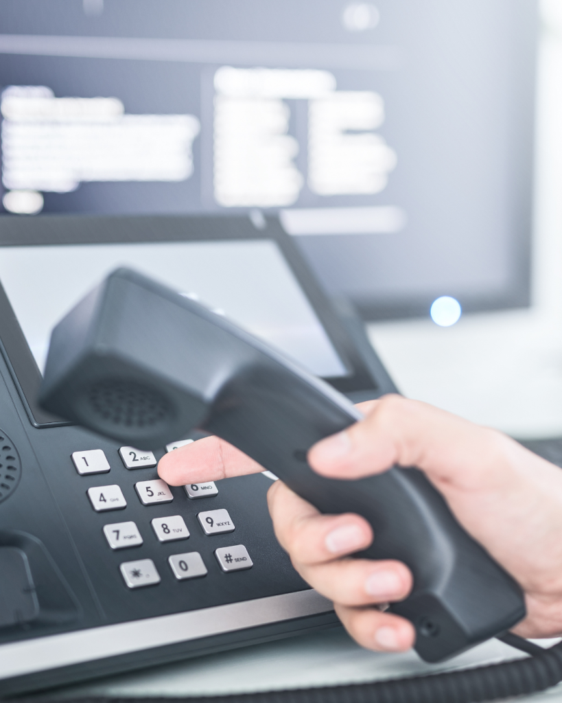 Person holding phone handset and dialing a number.